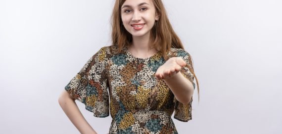 young girl with long hair wearing colorful dress contact with someone looking confident smiling standing over white background